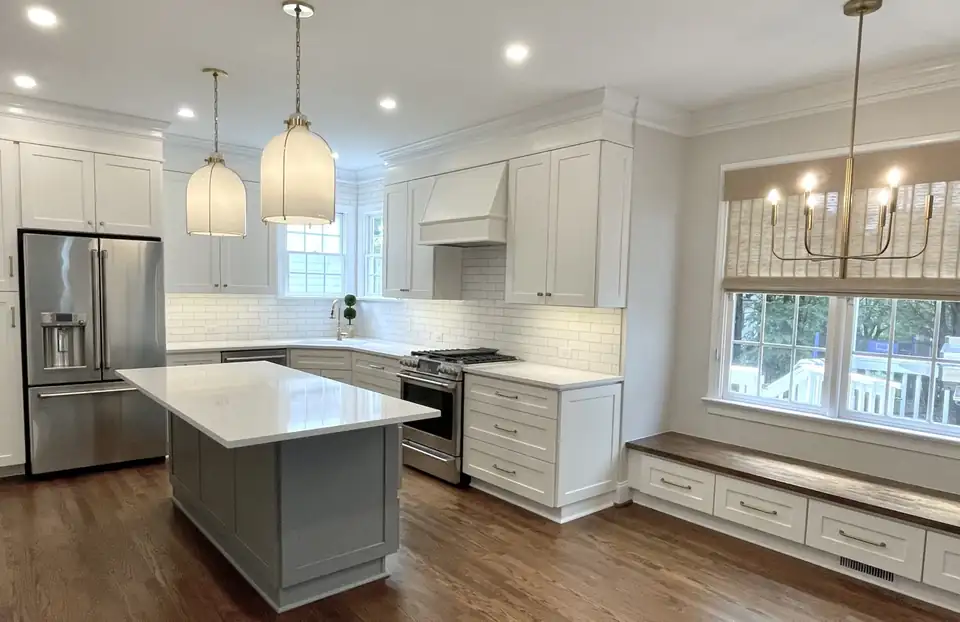 Kitchen remodeling Raleigh NC: West Raleigh kitchen with white shaker cabinets, gray island, glass pendant lights and a built-in window bench