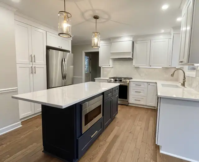 Cary, NC kitchen remodel with white shaker cabinets, navy island, quartz counters and lantern pendants