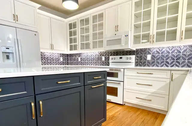 Kitchen with white glass-front upper cabinets, a navy island with brass pulls and a blue petal tile backsplash